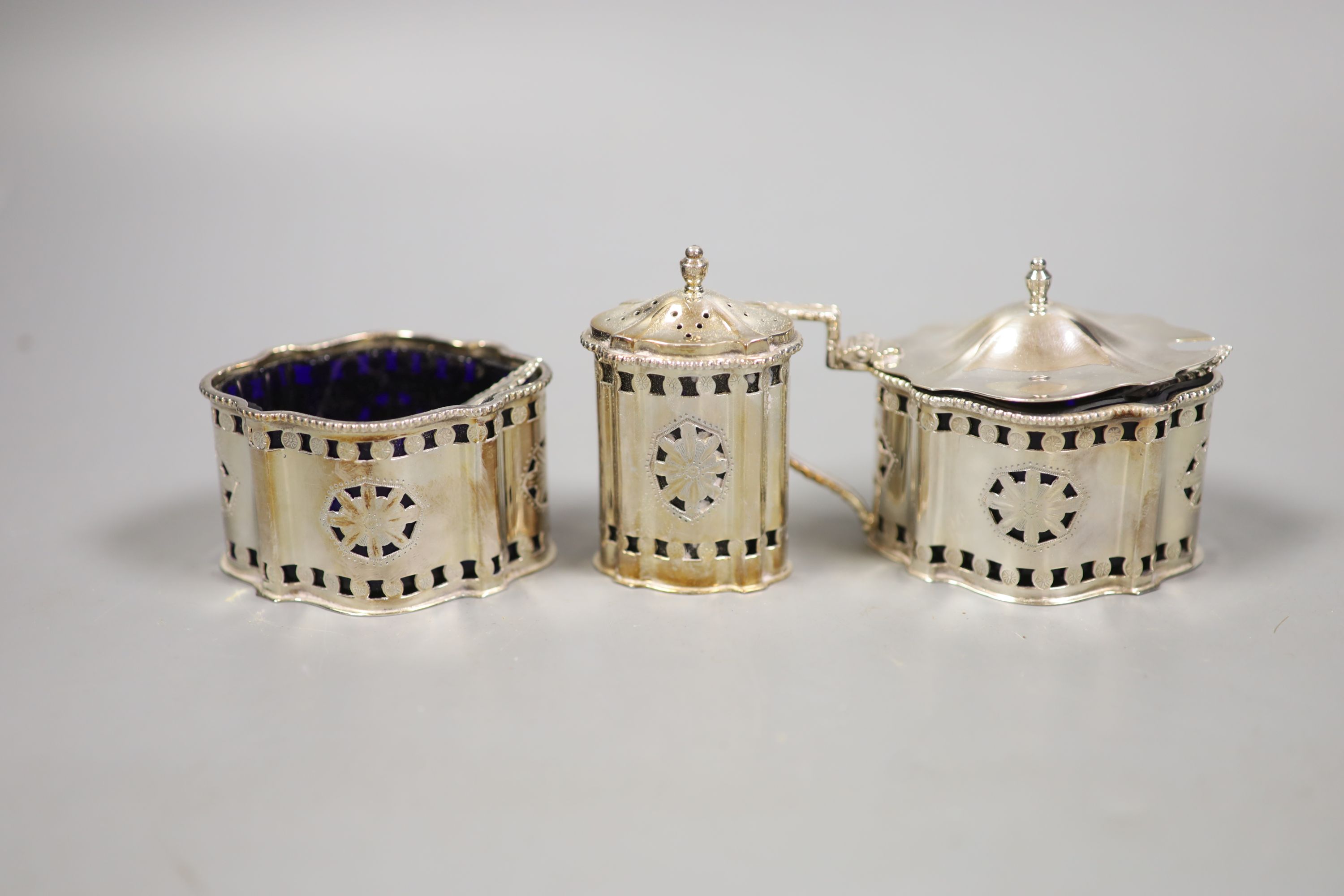 A modern George III style pierced and engraved shaped overal three peice condiment set